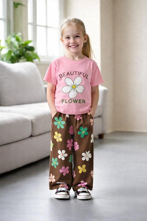 Child wearing a pink shirt with a flower design and brown pants with colorful flowers indoors.