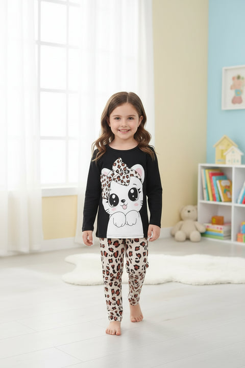 A kids' pajama set with a black top featuring a cute kitty face and cheetah print pants, displayed with a small stuffed animal and decorative items.