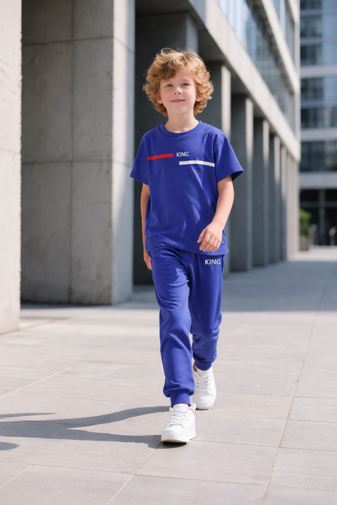 Child wearing a blue tracksuit with branding walking on a sidewalk.
