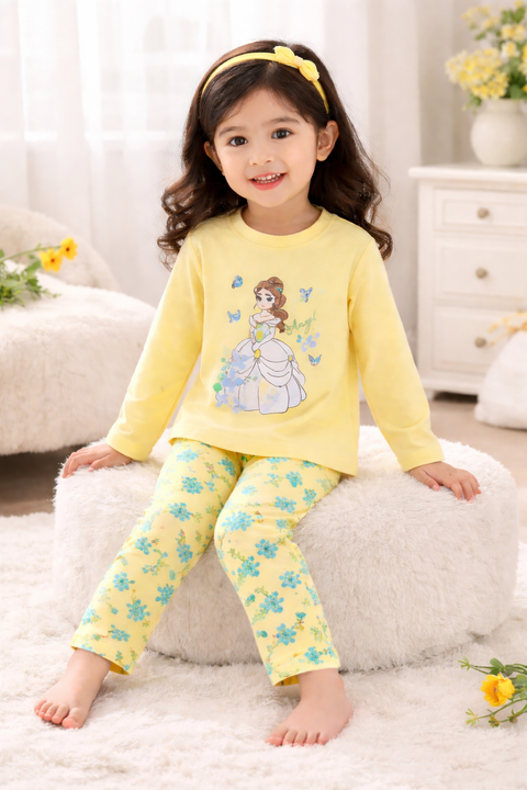 Child wearing a yellow outfit with a princess design, sitting on a white cushion.