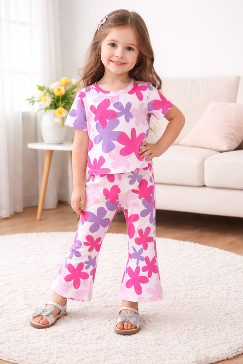 Young girl wearing a pink floral pajama set in a living room.
