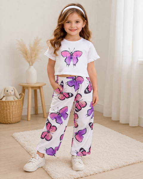 Young girl wearing a white t-shirt and pants with butterfly patterns in a room.