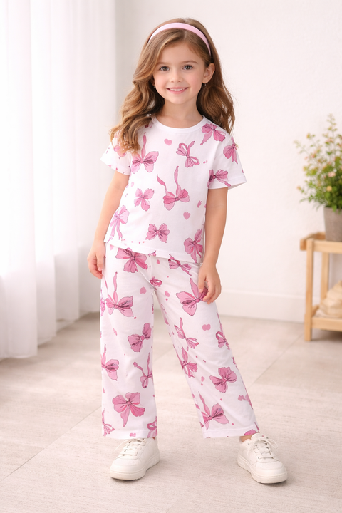 Young girl wearing a white outfit with pink butterfly patterns in a bright room.