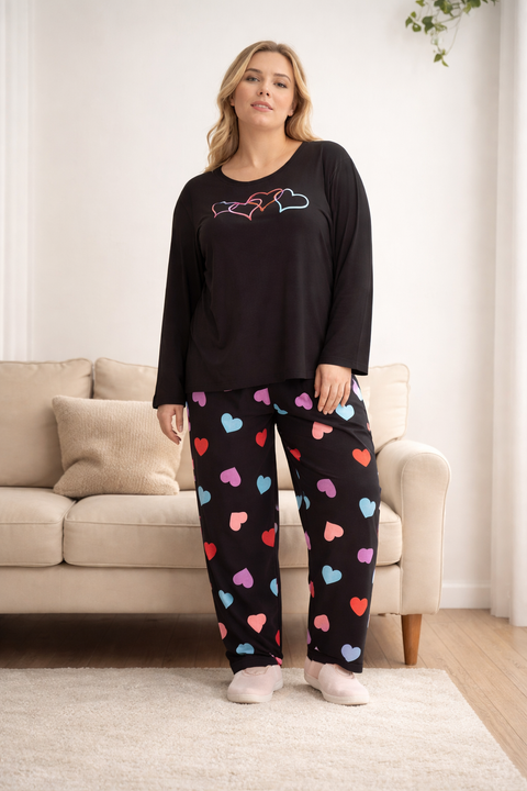 Woman wearing a black top with a colorful heart pattern on pants in a living room.