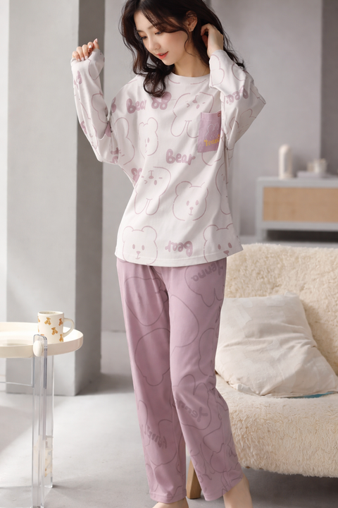 Woman wearing a matching pajama set with a white top and pink pants in a room.